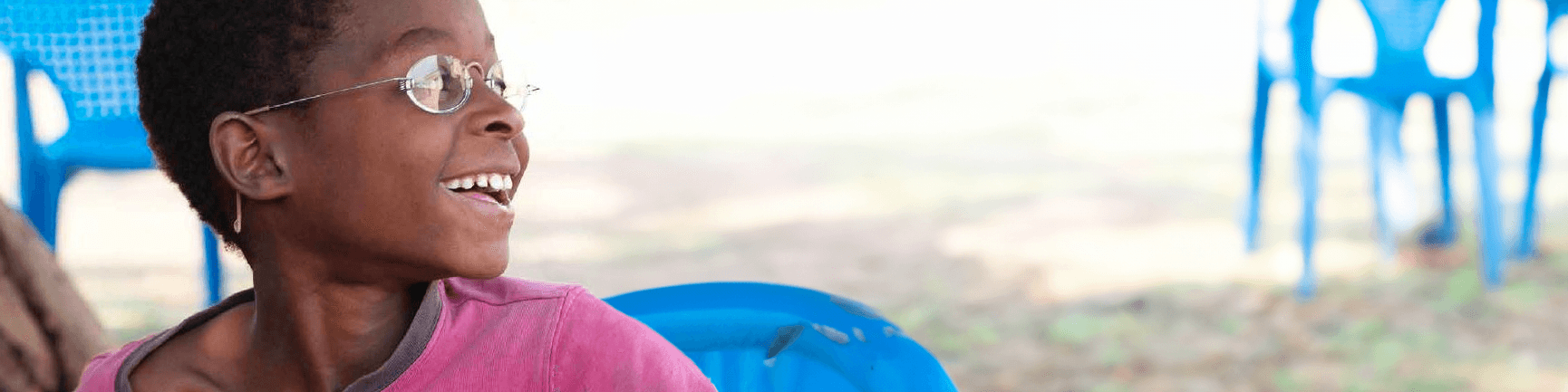 Junge mit Brille auf blauen Stuhl