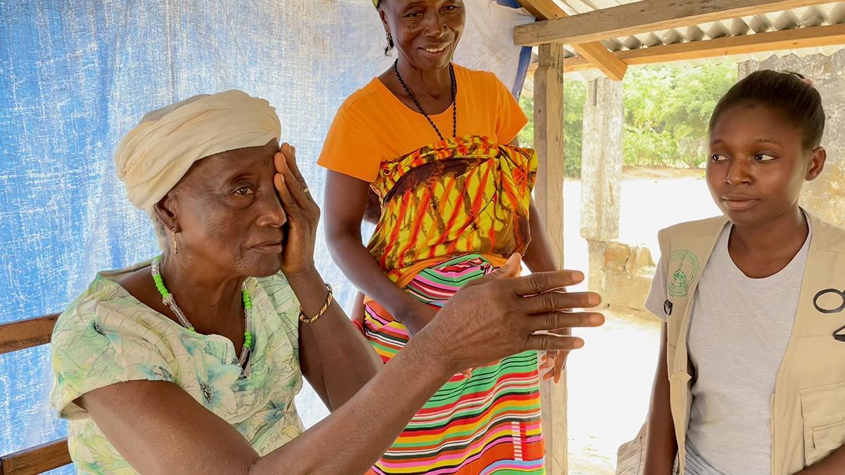 Situation beim Sehtest: Eine Mitarbeiterin von GoodVision Liberia sitzt neben Patientin, die sich ein Auge zuhält und mit der anderen nach links zeigt