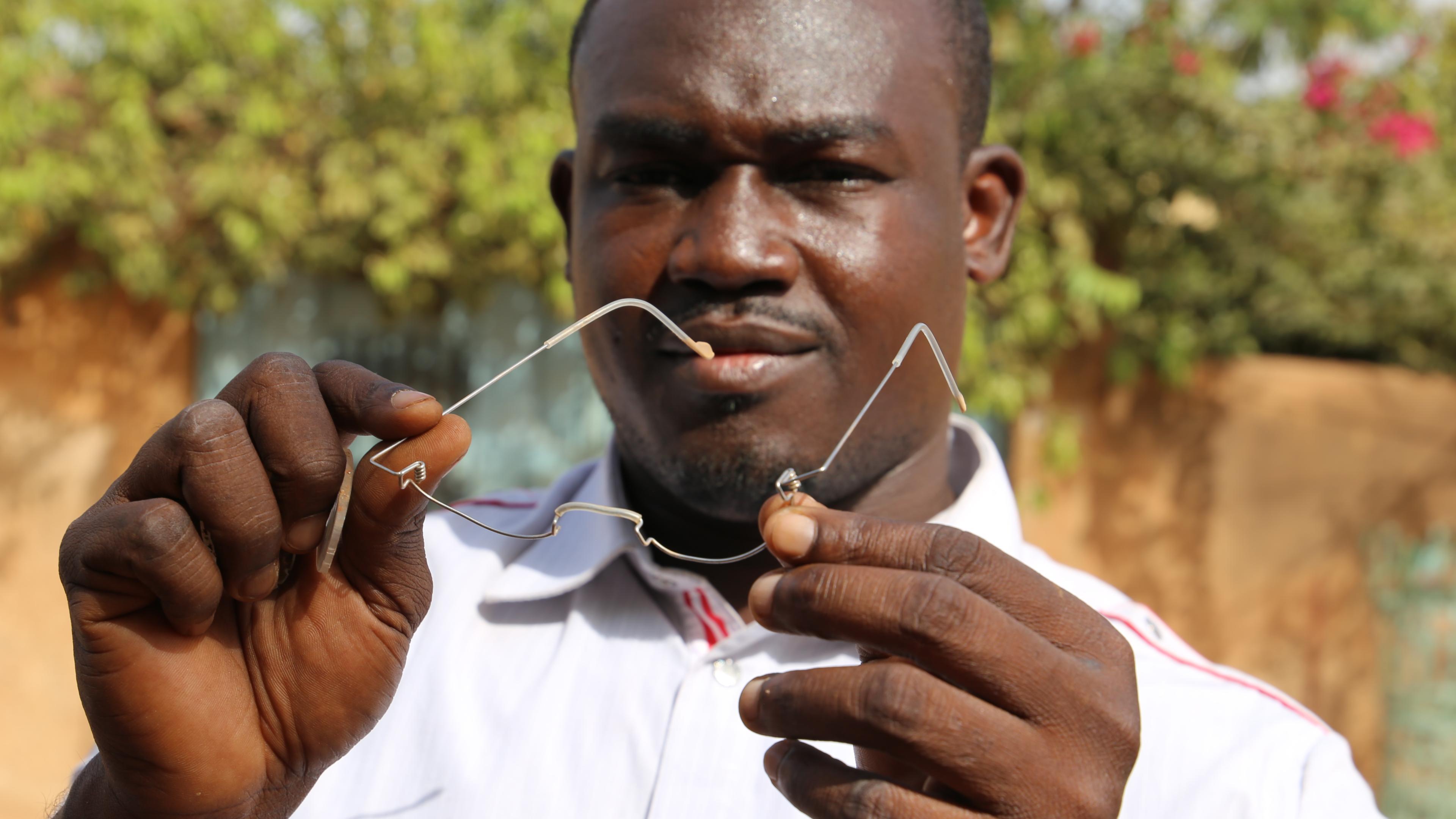 Mitarbeiter von GoodVision Burkina Faso hält verbogene EinDollarBrille