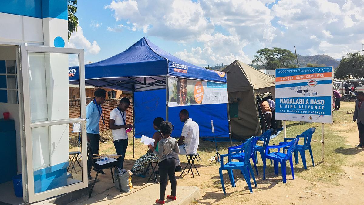 Impression vom Augencamp: Ein Pavillon zum Sonnenschutz mit Infoplakaten zur Augenkampagne, daneben angeschnitten ein GoodVision Shop