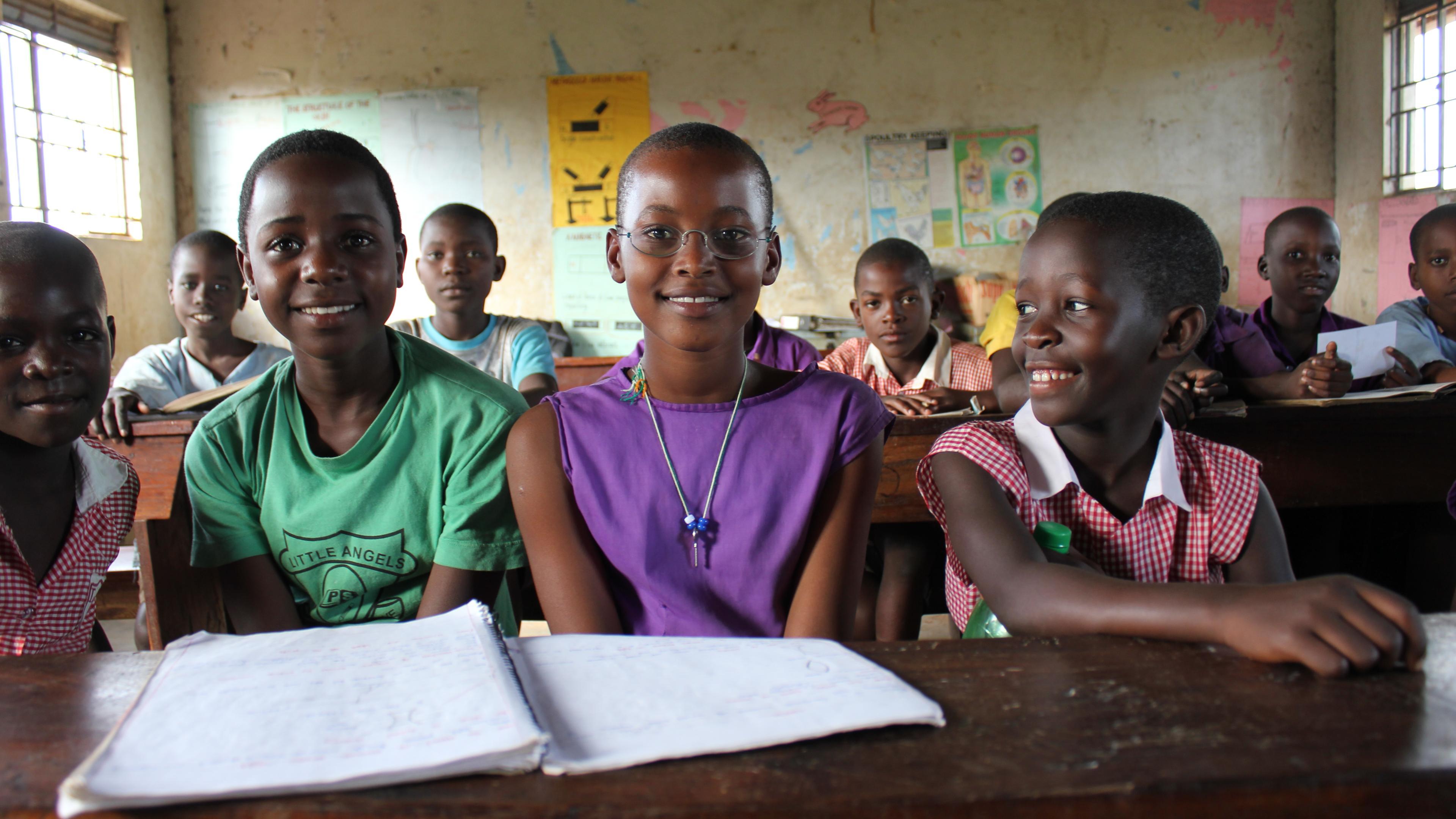 Schülerinnen aus Uganda im Klassenzimmer, eine trägt EinDollarBrille