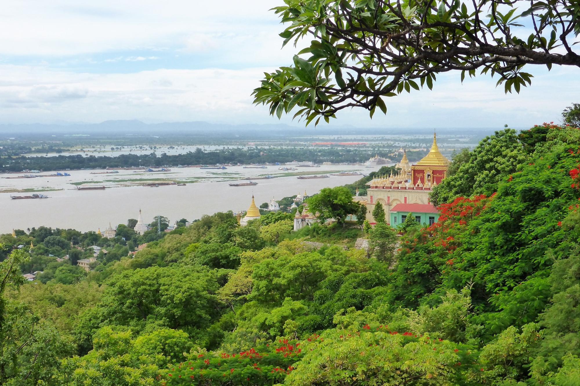 Panorama in Myanmar, grüne Wälder, Tempel mit goldenen Dächern, Fluss im Hintergrund