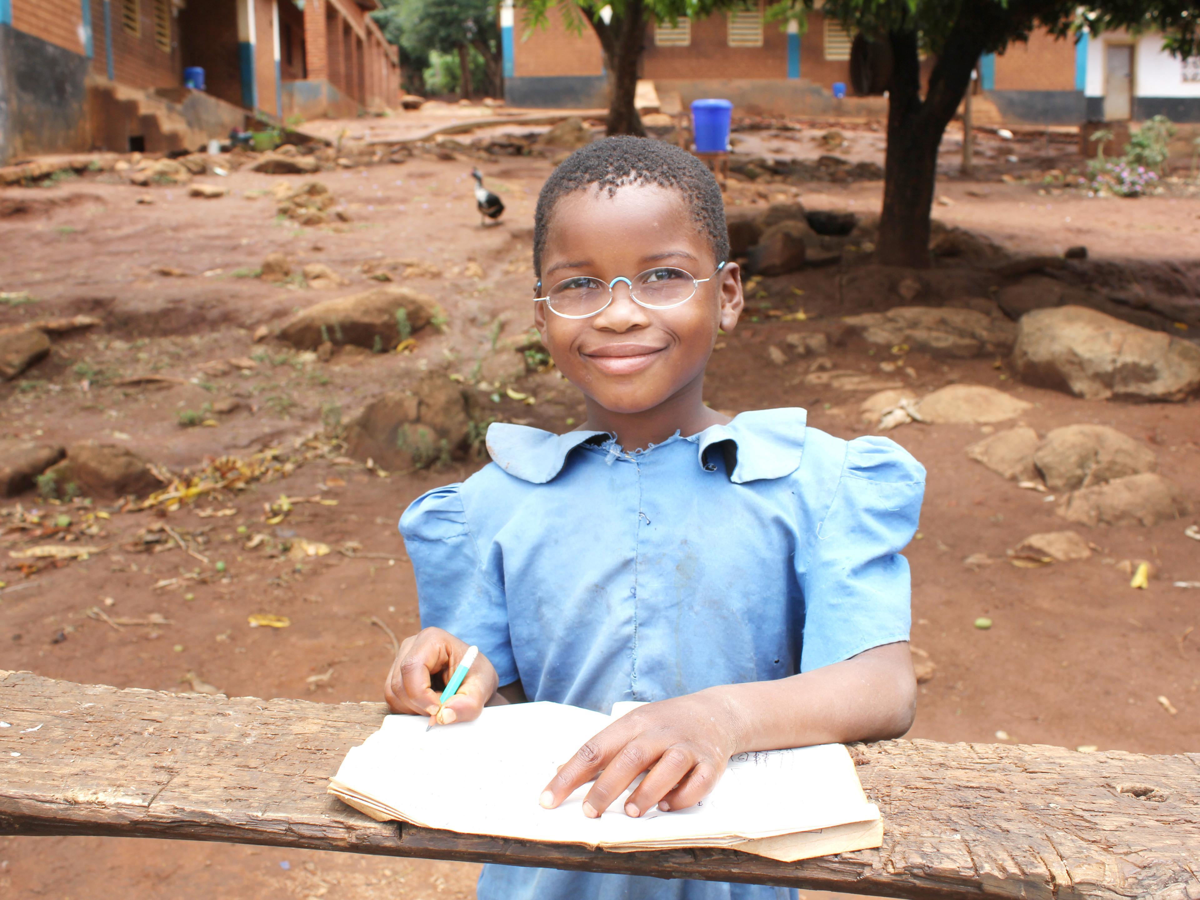 Schülerin aus Malawi, mit Schulheft und Stift, trägt EinDollarBrille